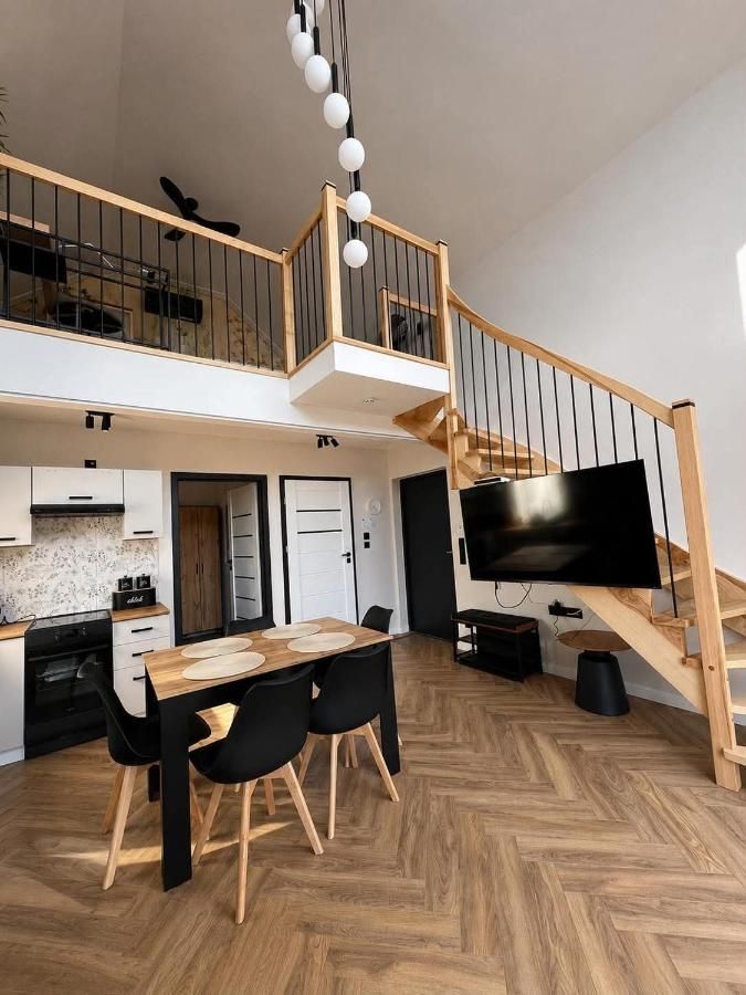 Salon z jadalnią, drewnianymi schodami i antresolą